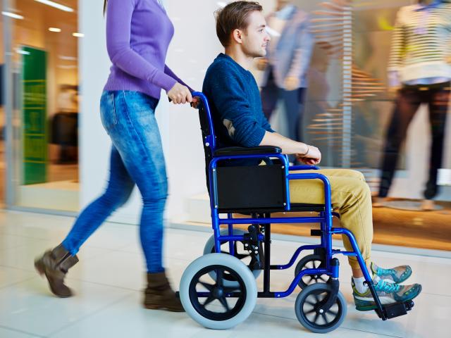 Physically impaired man in wheelchair doing shopping with his girlfriend in mall